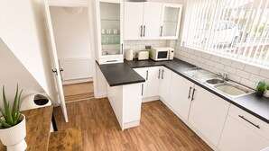 A modern kitchen with white cabinets, a black countertop, and a wooden floor.