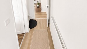 A hallway with a white radiator, a hanging light fixture, and a door leading to another room.