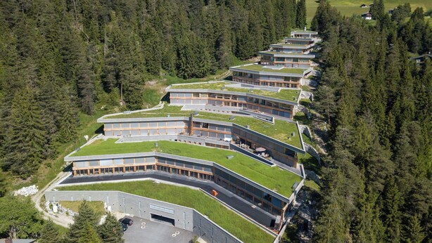 A modern building with a green roof, surrounded by dense forest. - Lovely apartment for 4 guests with WIFI, patio, pets allowed and panoramic view (Laax)