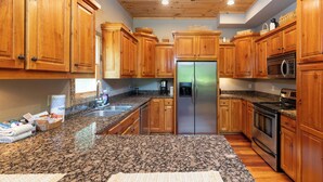 A kitchen with wooden cabinets, granite countertops, stainless steel appliances, and a wooden ceiling. - Rookery-High-Rollers, Hiking & Hot Tubs–Ultimate Motorcycle-Friendly Retreat! (Whittier)