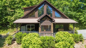 A wooden cabin with a gabled roof, large windows, and a porch with chairs. - Rookery-High-Rollers, Hiking & Hot Tubs–Ultimate Motorcycle-Friendly Retreat! (Whittier)