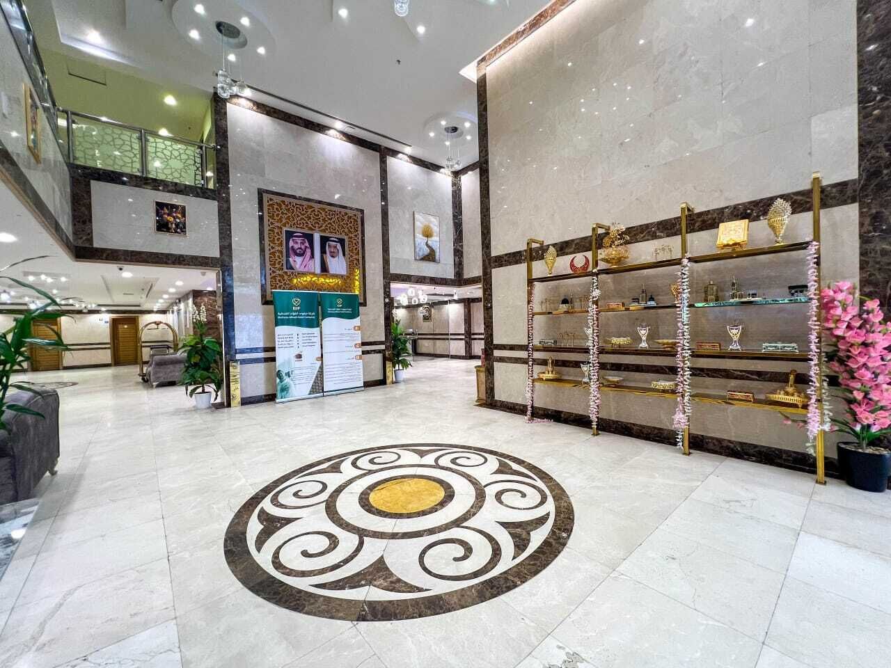 Un hall d’entrée spacieux, agrémenté d’un motif décoratif au sol, d’un comptoir de réception et d’une vitrine où sont exposés des trophées.