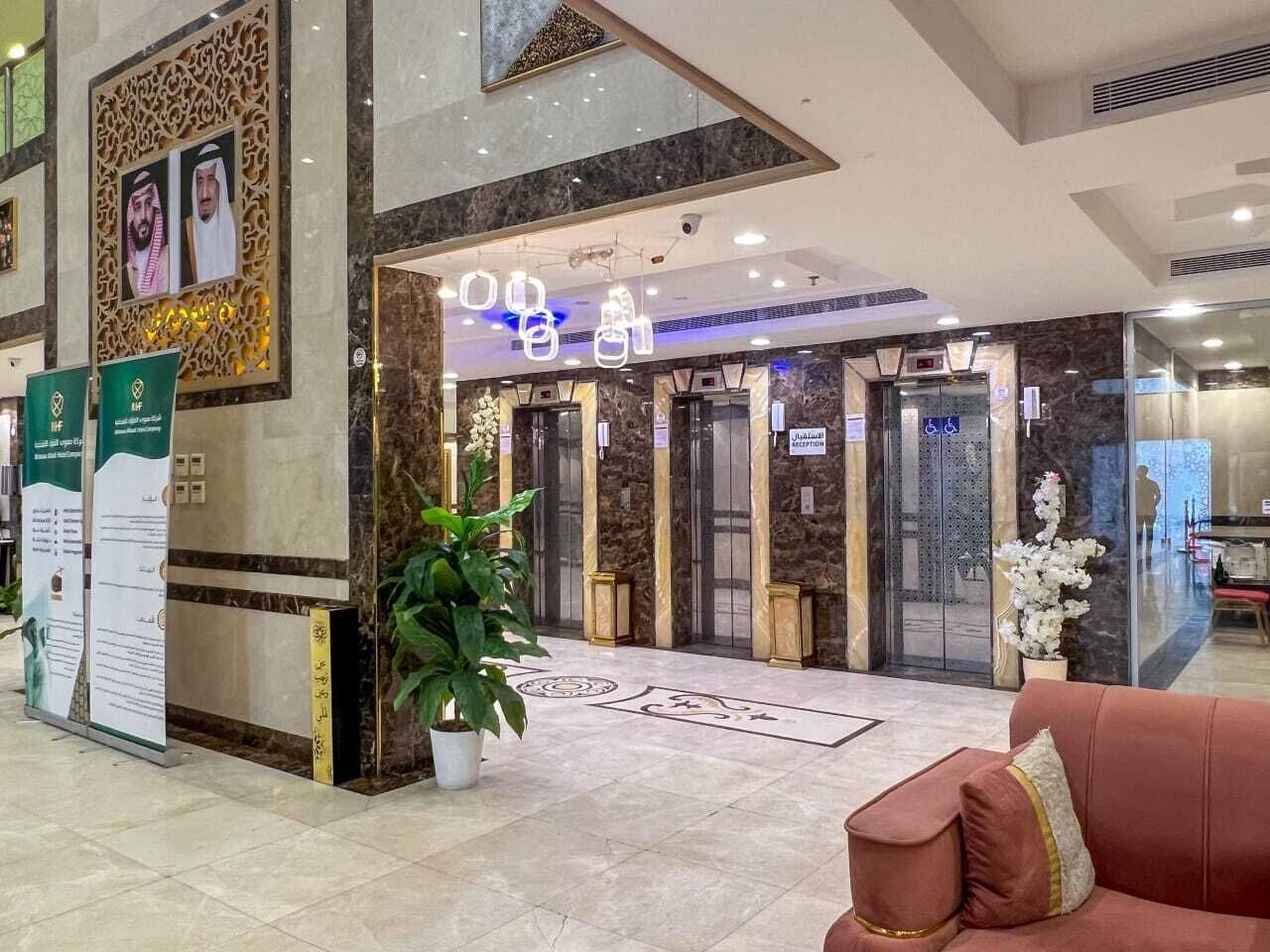 A lobby with marble flooring, a reception desk, a potted plant, and a red sofa.