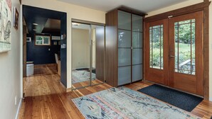 A modern interior with a wooden floor, a sliding glass door leading to a garden, and a large cabinet with frosted glass panels. - Rustic & Serene Forest 4 Bedroom Home - West Coast Retreat (Willis Point)