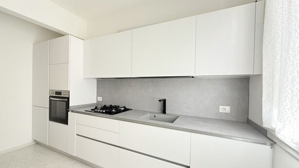 A modern kitchen with white cabinets, a built-in oven, a gas stove, and a sink.