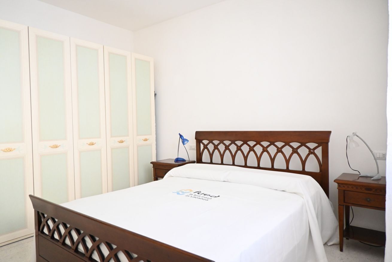Une chambre à coucher avec un lit en bois, une table de chevet, un bureau et une armoire.