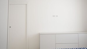 A white room with a closed door, a white wardrobe, and a wall-mounted air conditioner.