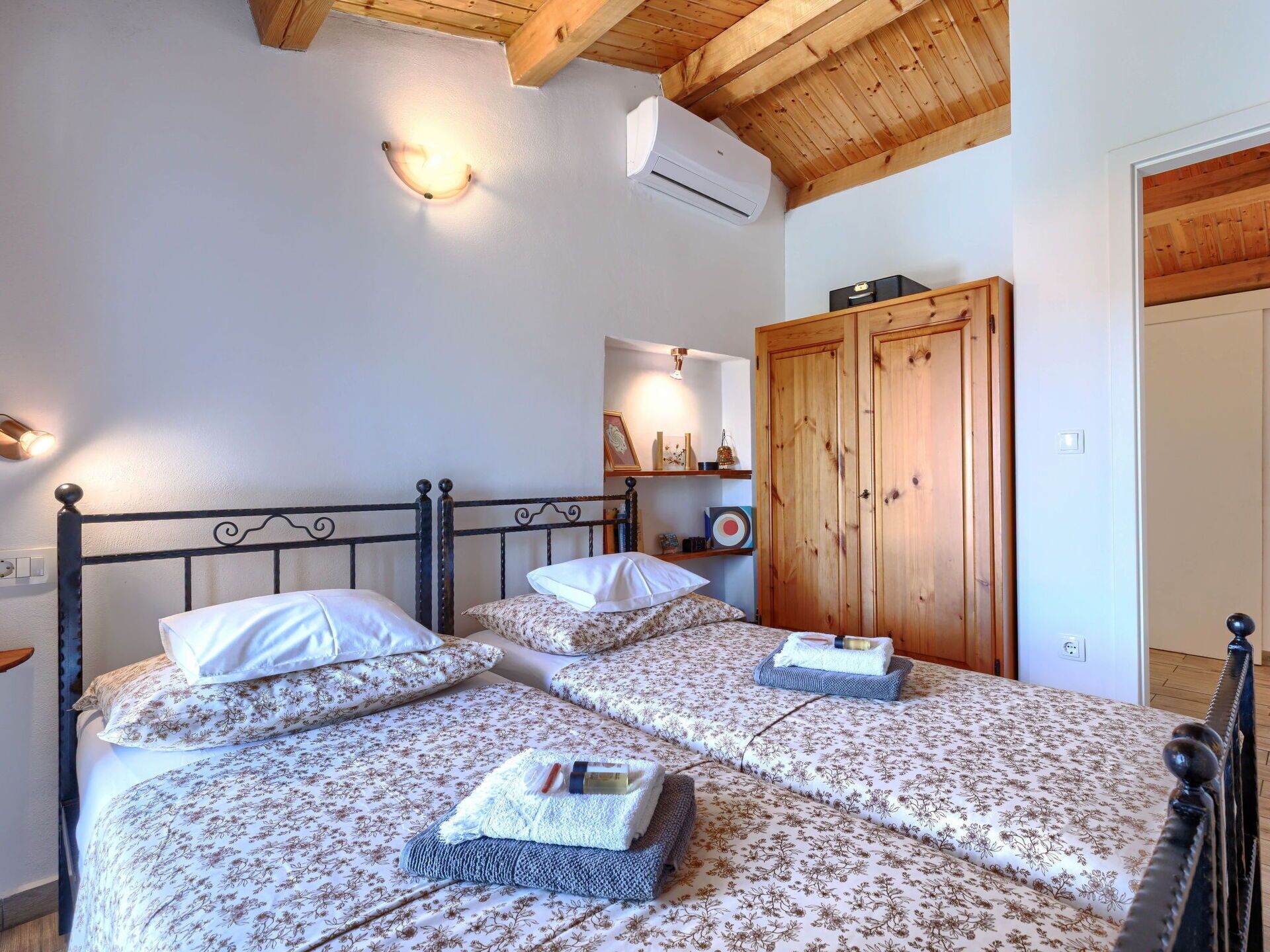 A bedroom with two beds, wooden wardrobe, and a ceiling fan.