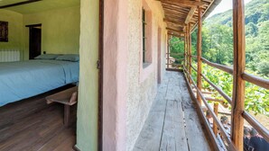 Un balcon en bois offrant une vue sur une colline boisée.