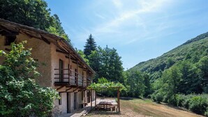 Un bâtiment rustique doté d’un balcon en bois, entouré d’un paysage naturel et surplombant un ciel dégagé.