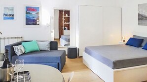 Een moderne kamer met een bank, een bed, een klein tafeltje met glazen en een fles.