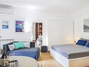 Ein modernes Zimmer mit einer Couch, einem Bett, einem kleinen Tisch mit Gläsern und einer Flasche.
