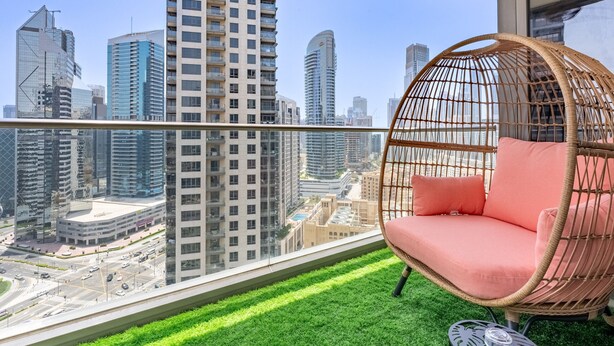 Un balcon avec un fauteuil en osier et une vue sur le paysage urbain.