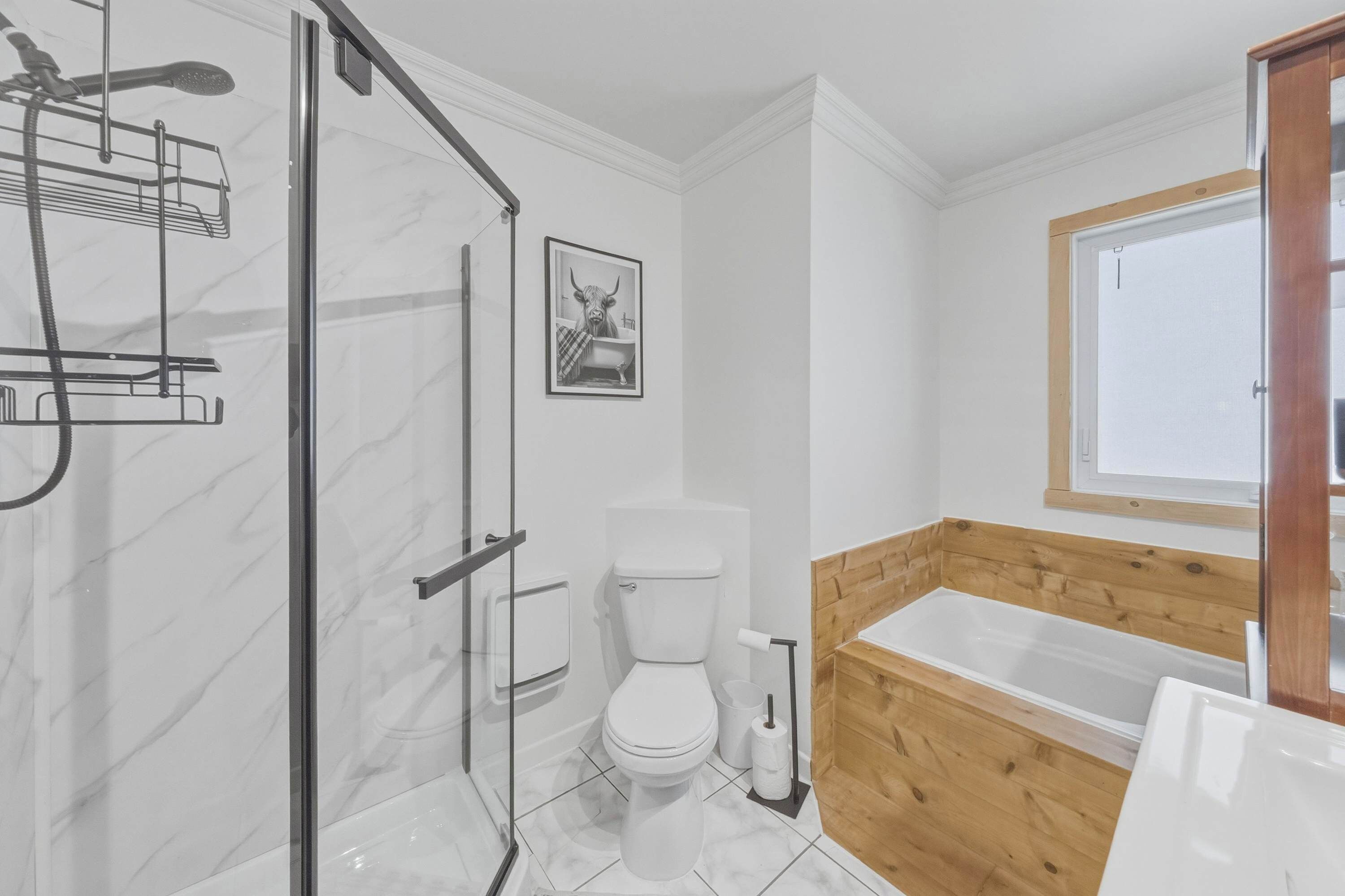 Une salle de bain avec une douche à parois de verre, des toilettes, une baignoire et un mur recouvert de panneaux en bois.