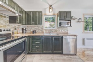 A modern kitchen with dark cabinetry, a built-in oven, a microwave, and a dishwasher.