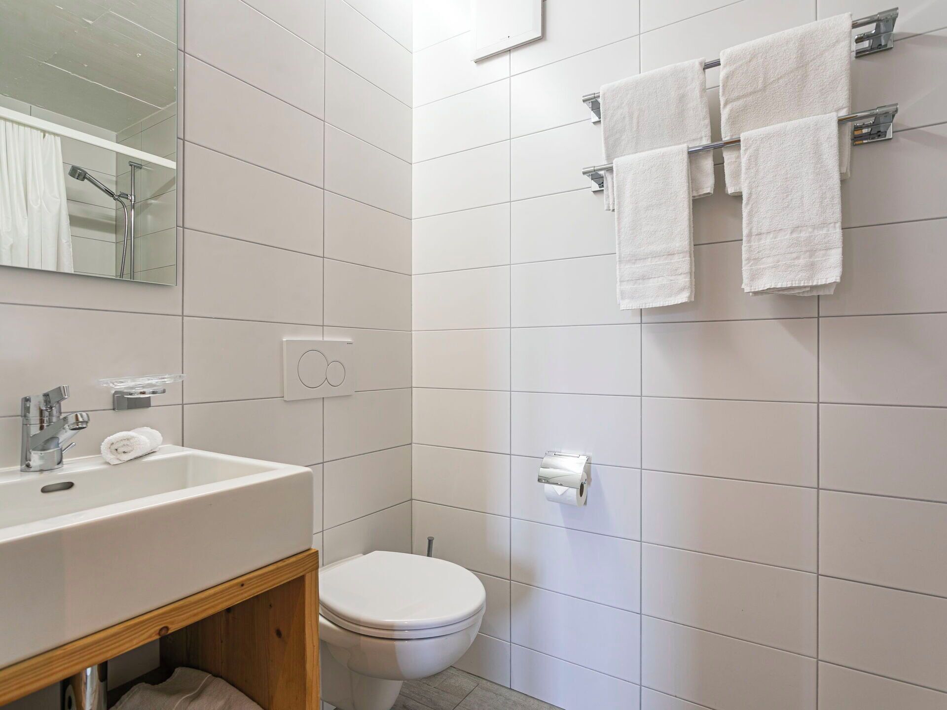 Een badkamer met een witte wastafel, toilet en handdoekhouder.