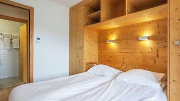 Une chambre à coucher avec une tête de lit en bois, un lit avec une literie blanche et deux appliques murales.