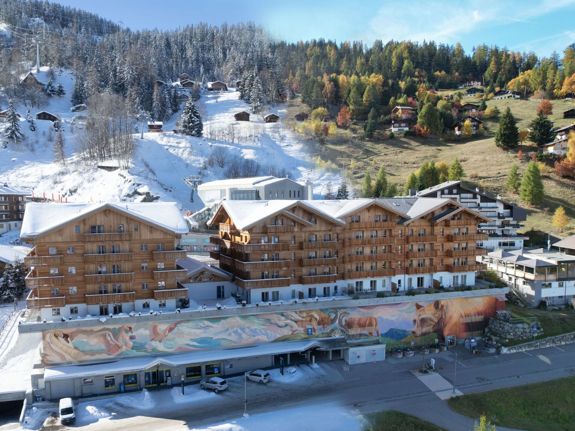 Un centro de esquí con edificios de madera, un mural y un paisaje cubierto de nieve.