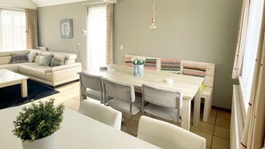 Un soggiorno moderno con zona pranzo, un divano, un tavolo e una lampada a sospensione.