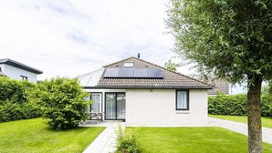 Una casa a un piano con tetto in tegole, un piccolo giardino e un vialetto lastricato che porta all'ingresso.