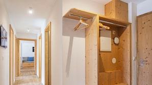 Een gang met houten vloer, een houten garderobe met spiegel en een bankje op de achtergrond.