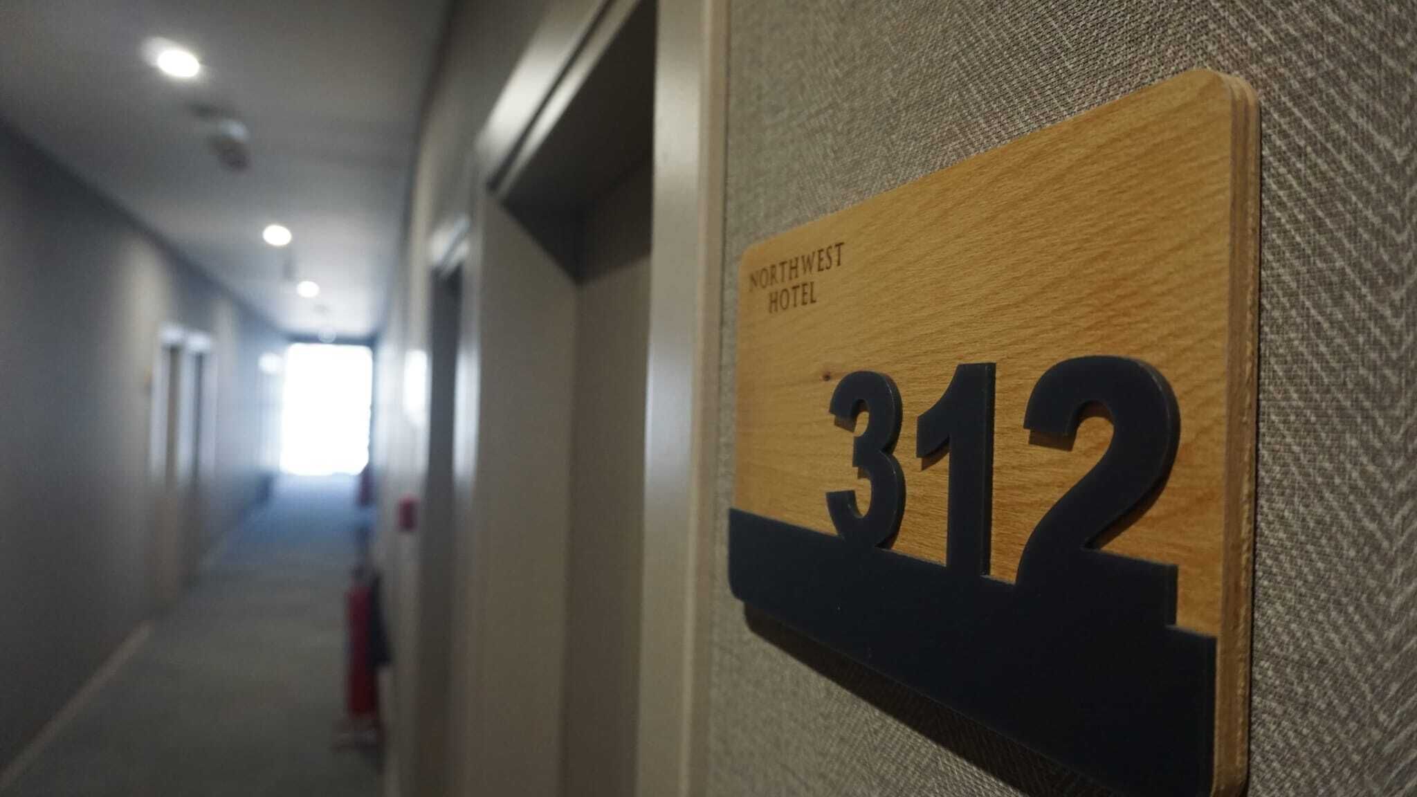 A hallway with a sign indicating room number 312 at the Northwest Hotel.