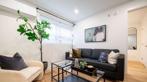 A modern living room with a sofa, a coffee table, a plant, and a painting on the wall. - Modern 1BR in the Heart of Ottawa (Ottawa)