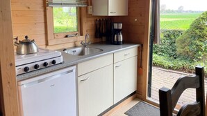 Eine kleine Küche mit Gasherd, Spüle und weißen Schränken.