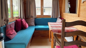 Ein gemütliches Cabin-Interieur mit einem blauen Sofa, Holzwänden und einem Fenster mit Vorhängen.