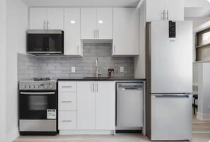 A modern kitchen with white cabinets, a built-in oven, a microwave, a refrigerator, and a dishwasher. - Bright Studio steps from University of Ottawa (Ottawa)