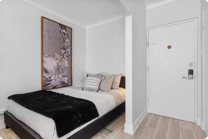 A bedroom with a bed, a door with a lock, and a large abstract painting on the wall. - Bright Studio steps from University of Ottawa (Ottawa)