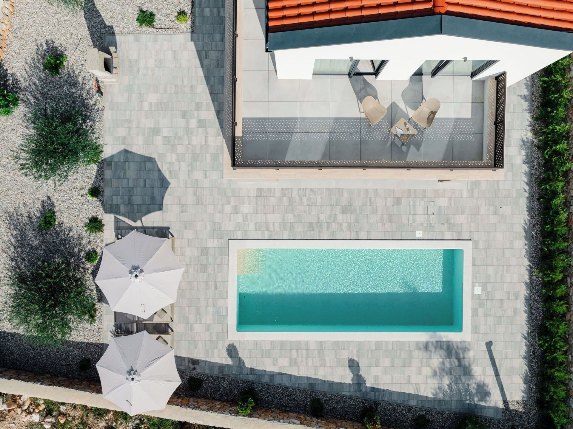 A rooftop pool area with a rectangular pool, outdoor seating, and a covered seating area.