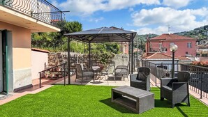 Eine Terrasse mit Gartenmöbeln, einer Pergola und einem gepflegten Rasen.