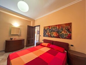 Een slaapkamer met een bed, een dressoir, een spiegel en een schilderij aan de muur.