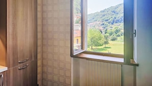Ein Badezimmer mit Fenster, Holzschränken und Heizkörper.