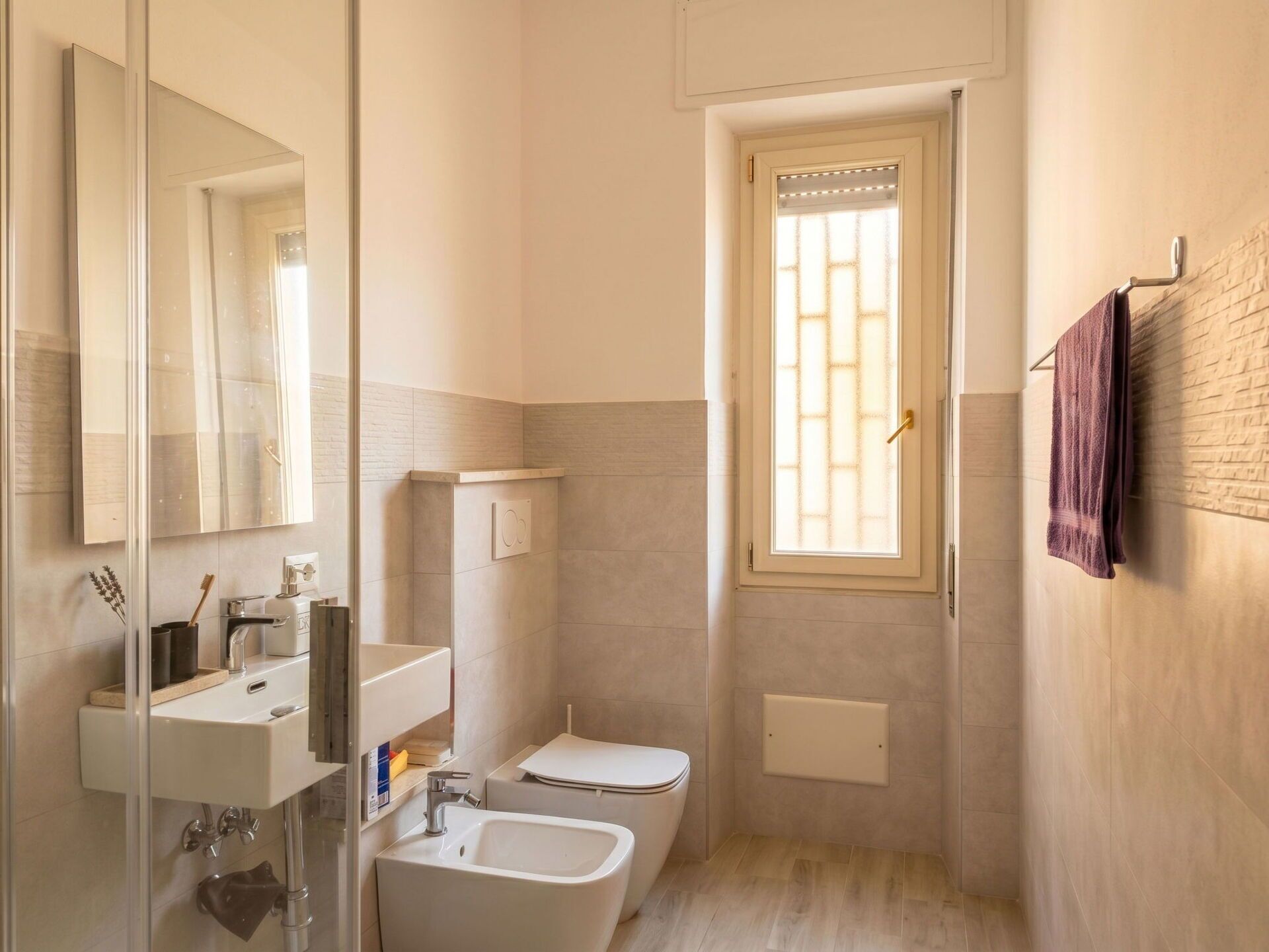 Een kleine badkamer met toilet, wastafel en raam.