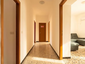 Corredor de hotel com uma porta no fim, um sofá verde e um chão estampado.
