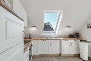 Een moderne keuken met witte kastjes, een houten aanrecht, een dakraam en een koffiezetapparaat.