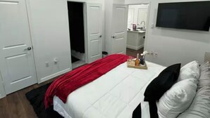 Un dormitorio con cama, ventilador de techo, televisión y espejo.