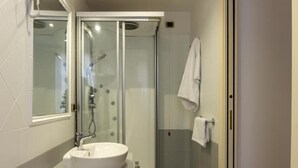 A modern bathroom with a glass-enclosed shower, a white sink, and a towel rack. - Mi Tú Apartments (Catania)