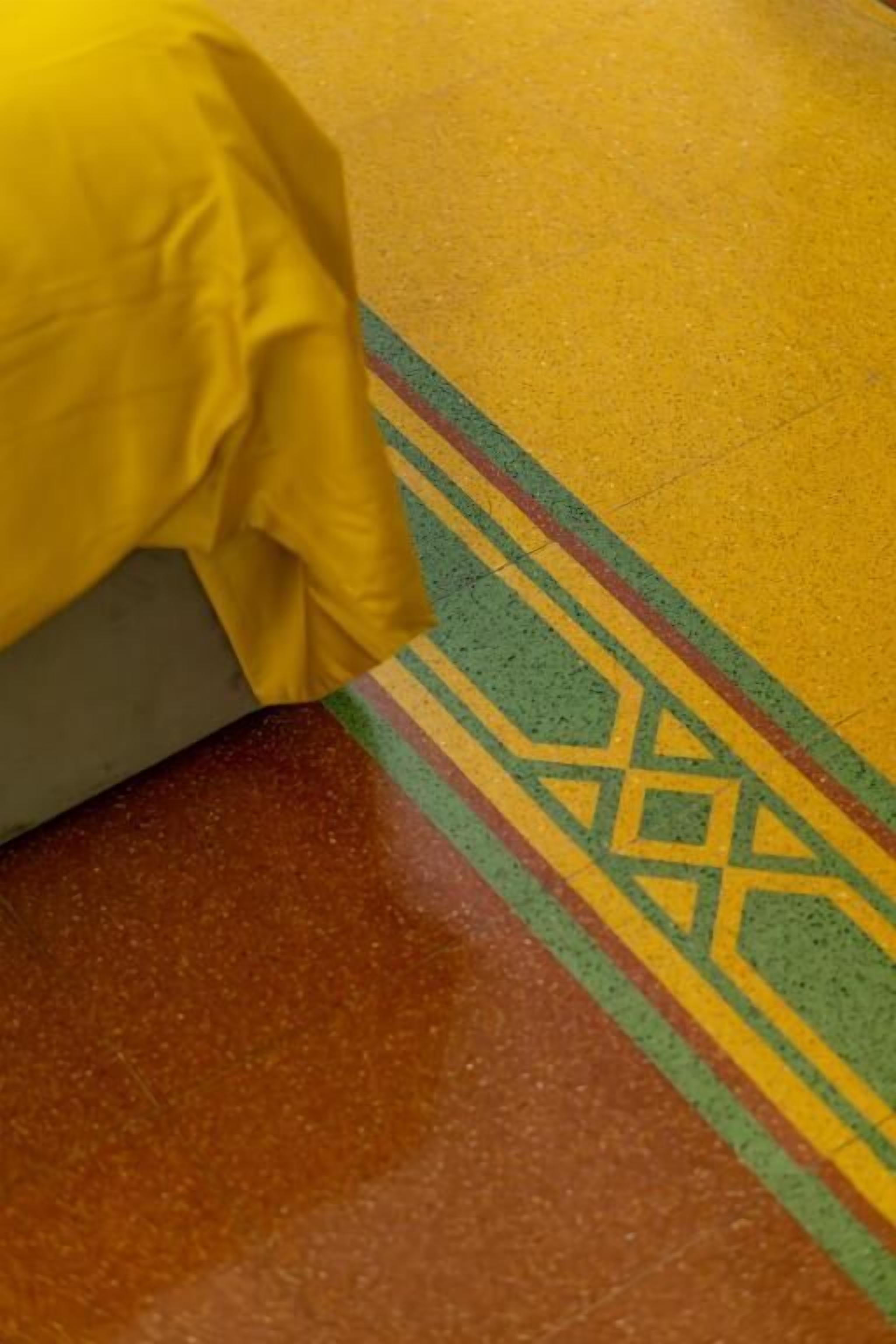 A patterned floor with a yellow object partially covering it.
