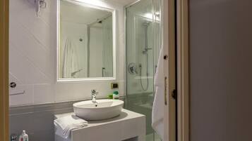 A bathroom with a glass shower enclosure, a white sink, and a mirror above it.