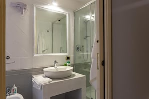 A bathroom with a glass shower enclosure, a white sink, and a mirror above it. - Mi Tú Apartments (Catania)
