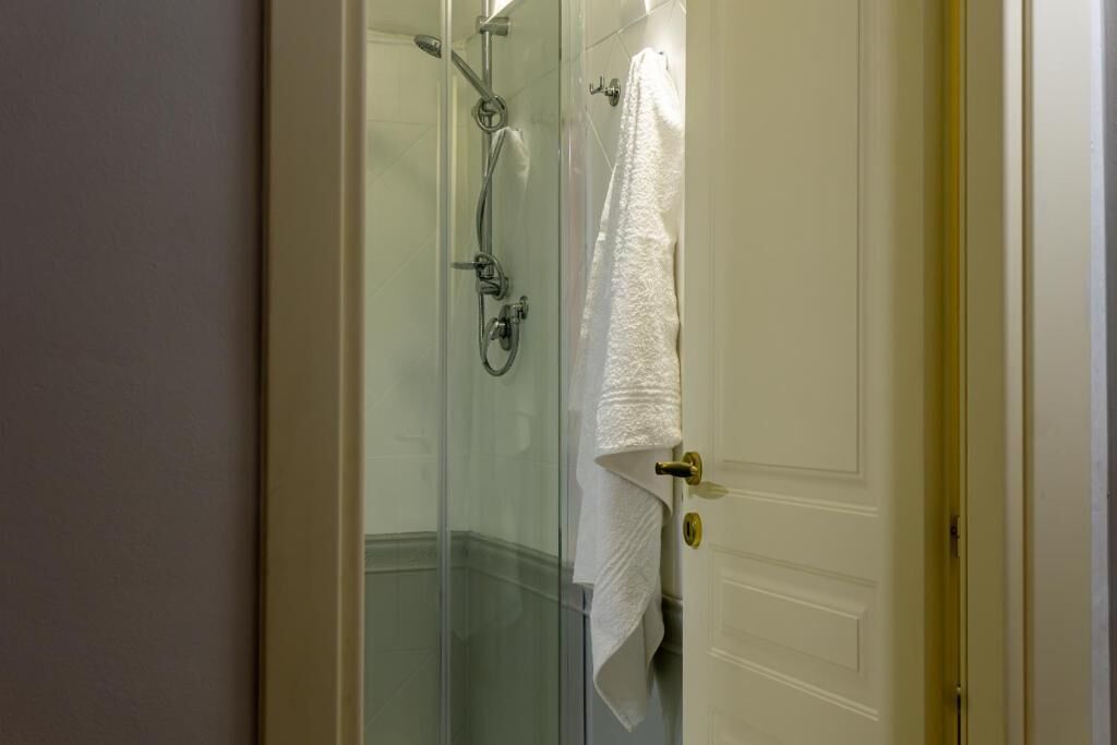 A glass-enclosed shower area with a towel hanging on the door.