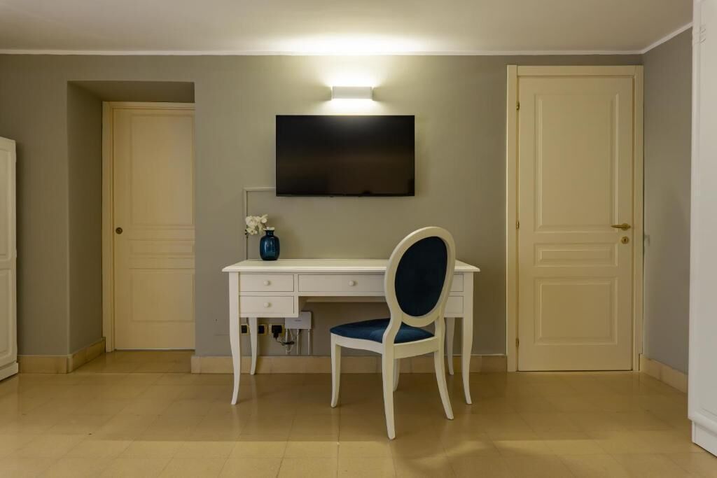 A room with a desk, chair, TV, and two doors.