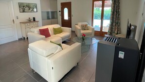 En rummelig opholdsstue med en hvid sofa, et glasbord og et sort køleskab.