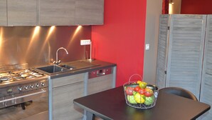 A kitchen with a gas stove, sink, and a fruit basket on the table. - Figuier Vacation Rental: Les Cerisiers 2, surrounded by nature near the Drôme River (Mirabel-et-Blacons)