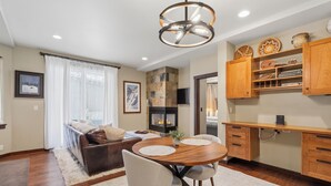 A cozy living room with a fireplace, a dining area with a wooden table, and a kitchen with wooden cabinets. - Alpine Creek #2 - Club Solitude Access, Walk to Lifts (Solitude)
