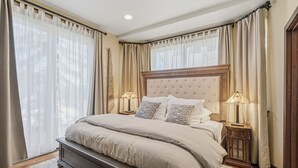 A bedroom with a large bed, two bedside tables with lamps, and sheer curtains. - Alpine Creek #2 - Club Solitude Access, Walk to Lifts (Solitude)