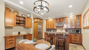 A modern kitchen with wooden cabinets, a stainless steel refrigerator, a built-in oven, and a bar area. - Alpine Creek #2 - Club Solitude Access, Walk to Lifts (Solitude)